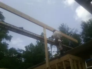 Carpenter setting a ridge beam over a new addition frame — Ice Dam Removal by Roofing Brothers in Lake Grove
