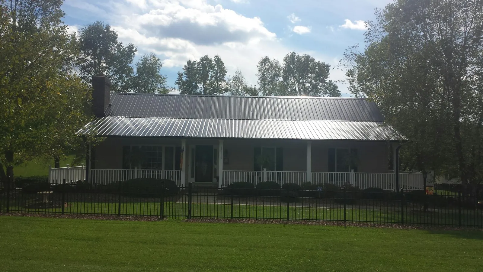 Gray metal roof on a brick ranch with a full width front porch — Gutter Guard Installation work by our crew in Lake Grove
