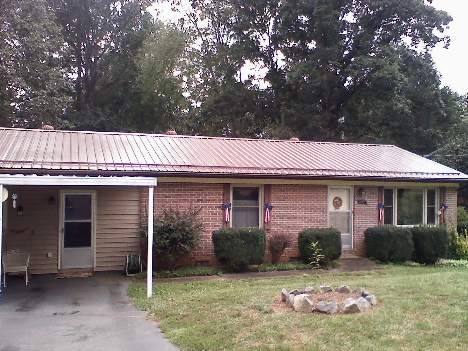 Bronze metal roof and carport on a brick ranch home — Roof Repair work by our crew in Lake Grove
