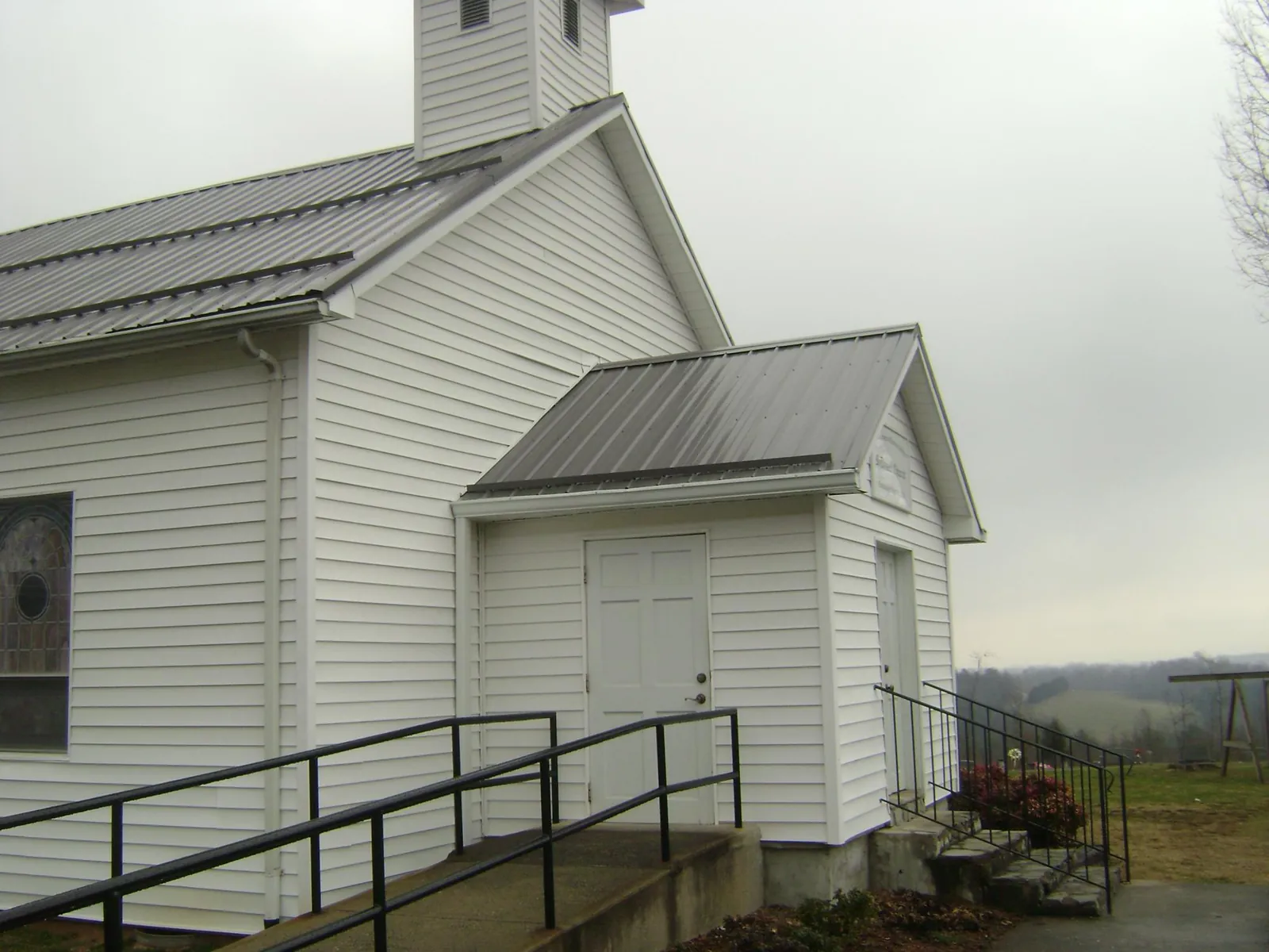 Gray metal roof on a white clapboard church with a steeple in Lake Grove